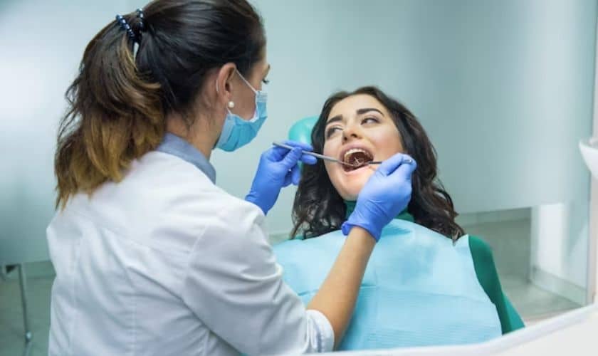 Dental hygienist examining patient's teeth during checkup at dentist office.