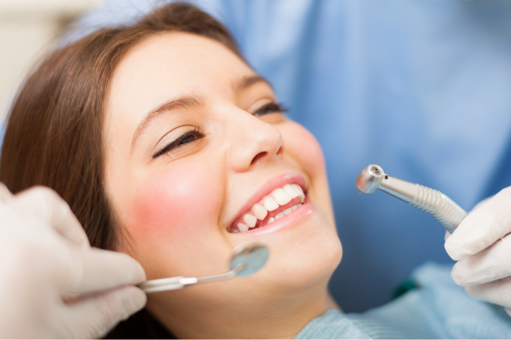 Woman smiling during dental examination with dentist's tools in Jupiter dental office.